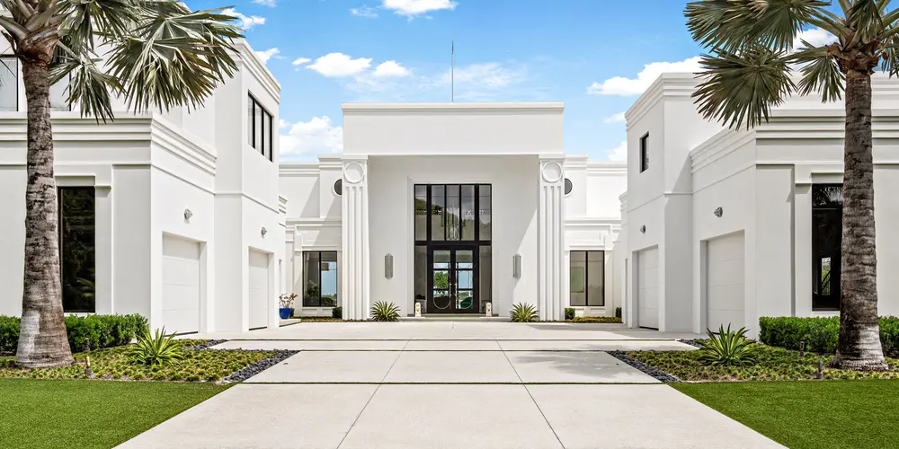 As you approach this modern residence, the architectural style is defined by its imposing yet elegant use of columns, which prominently frame the entrance. These columns serve as a nod to classical influences while maintaining a contemporary aesthetic, blending the old with the new. The home's facade, with its minimalist lines and symmetry, creates a sophisticated entrance that commands attention. The overall style is reminiscent of neoclassical architecture, but with a modern twist that emphasizes neoclassical Art Deco architecture.