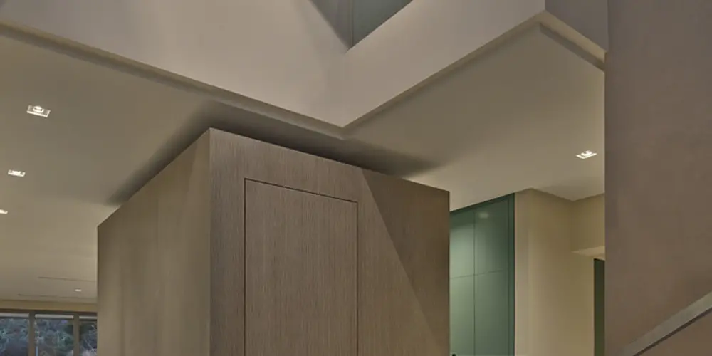 This foyer combines sleek lines and minimalist design with artistic flair, highlighted by a wall sculpture. Glass railings and light wood textures create a sophisticated, airy atmosphere.

